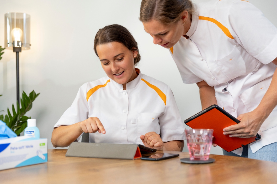 Twee verpleegkundigen kijken op een tablet
