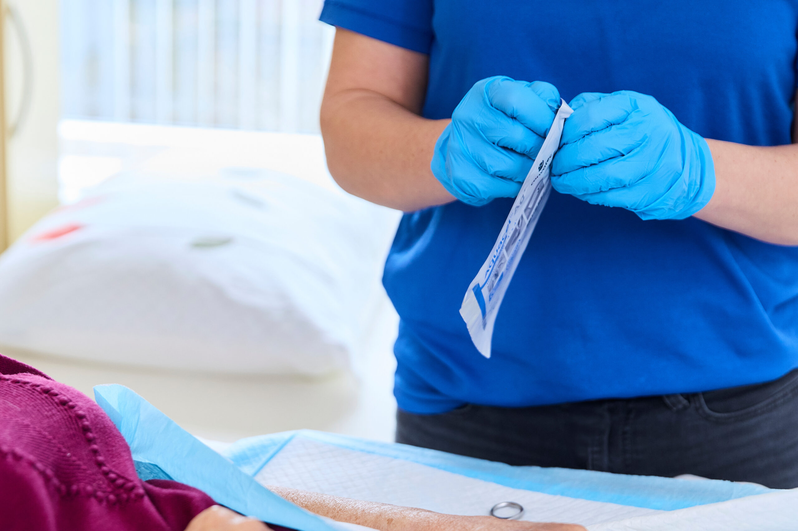Verpleegkundige opent wondverband aan bed van patiënt