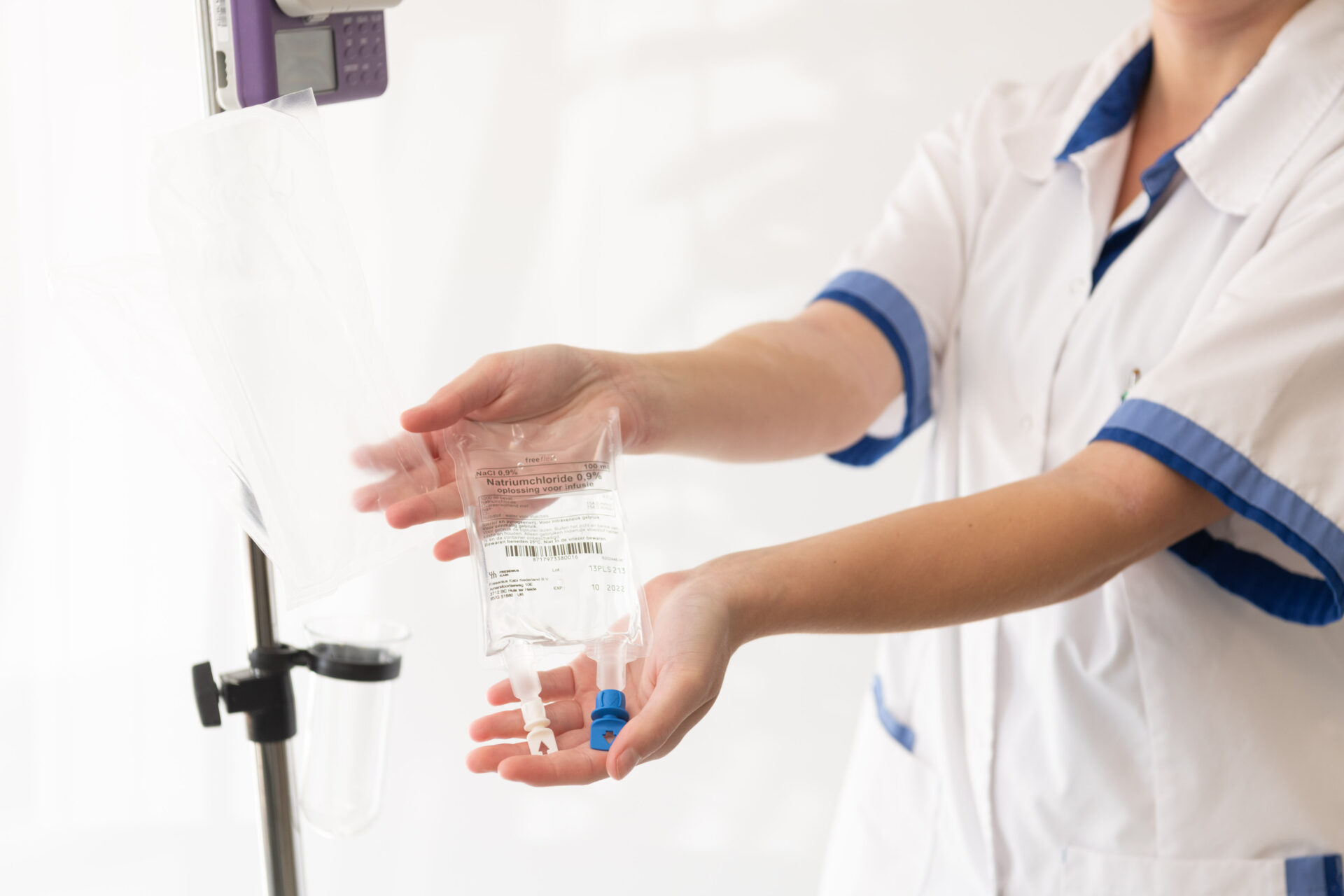 Verpleegkundige houdt infuuszak gevuld met NaCl 0,9% vast