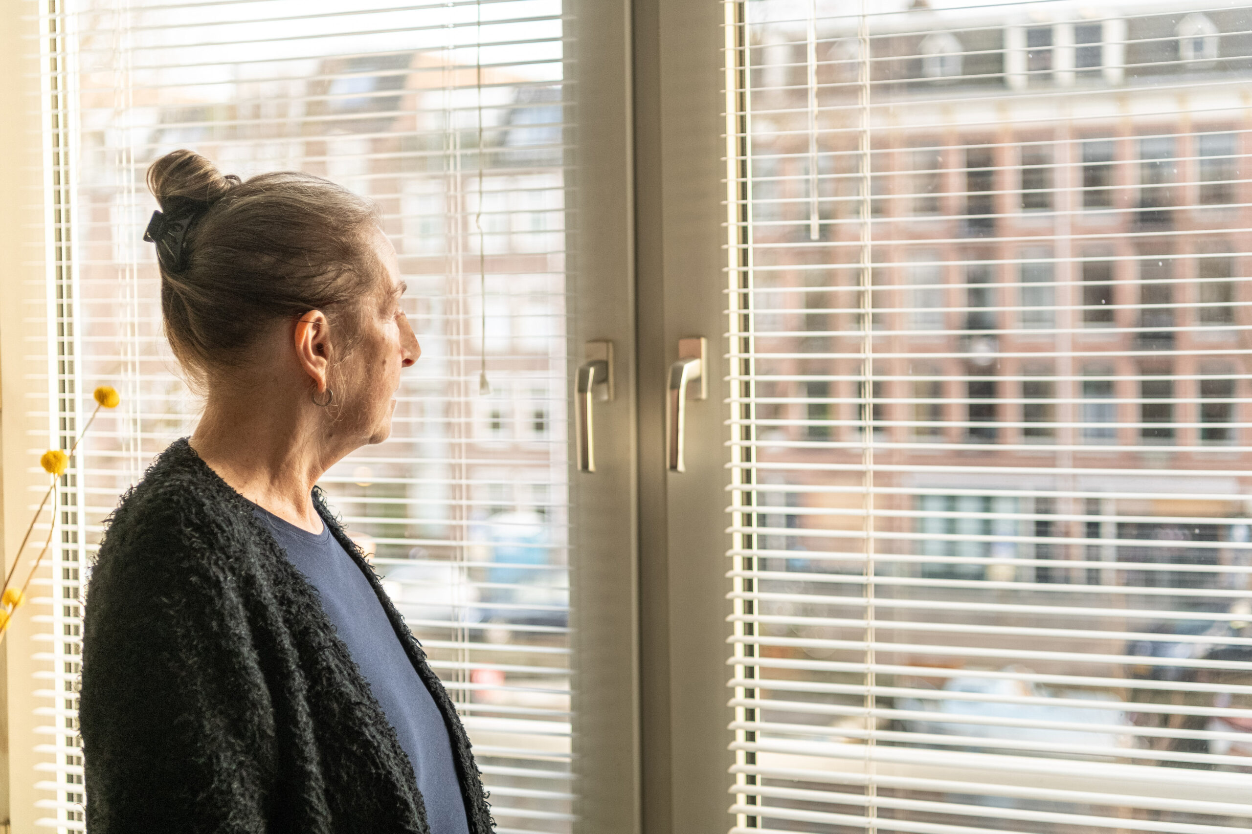 vrouw kijkt uit raam zorgmijder
