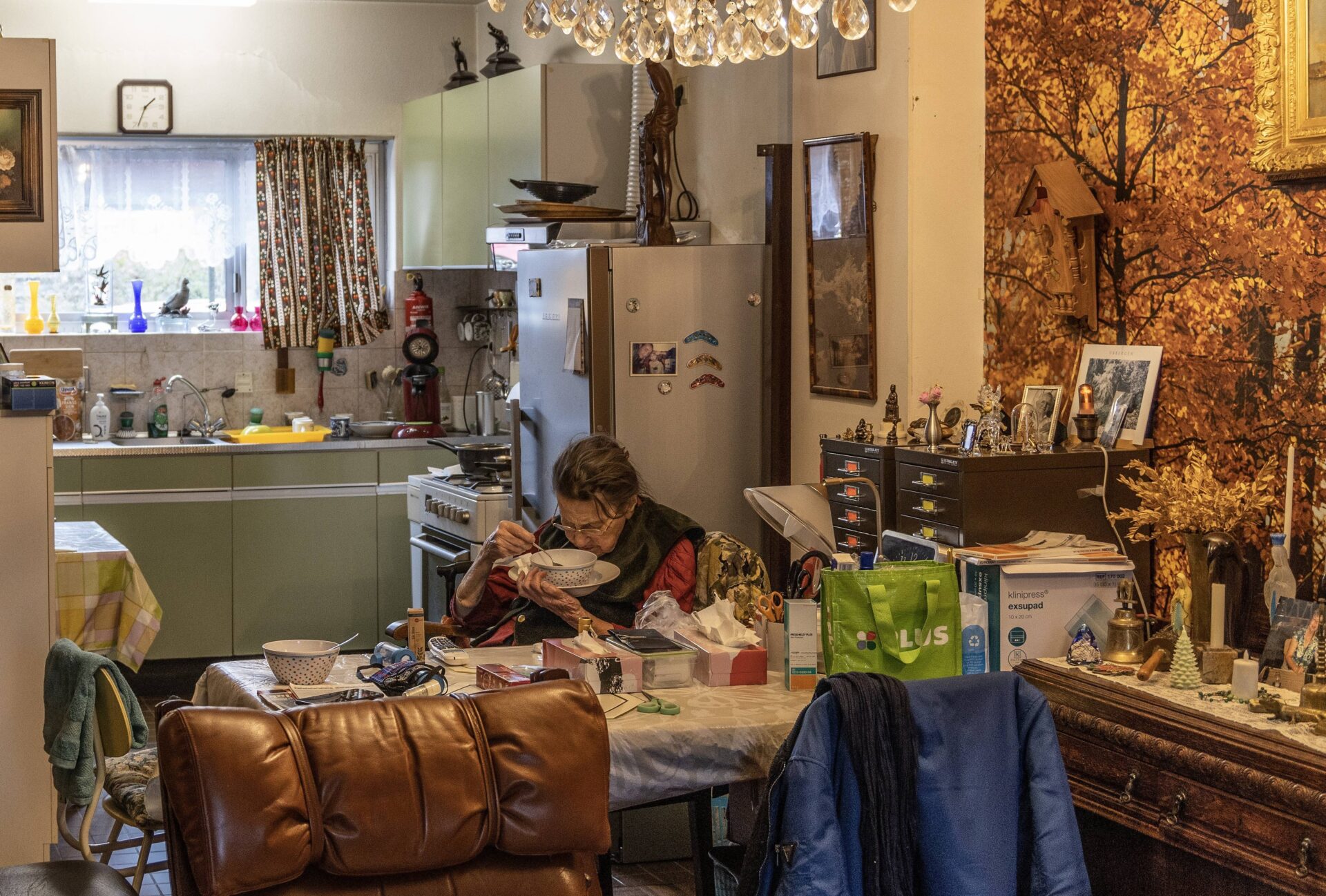 Oudere vrouw eet soep in een druk interieuer