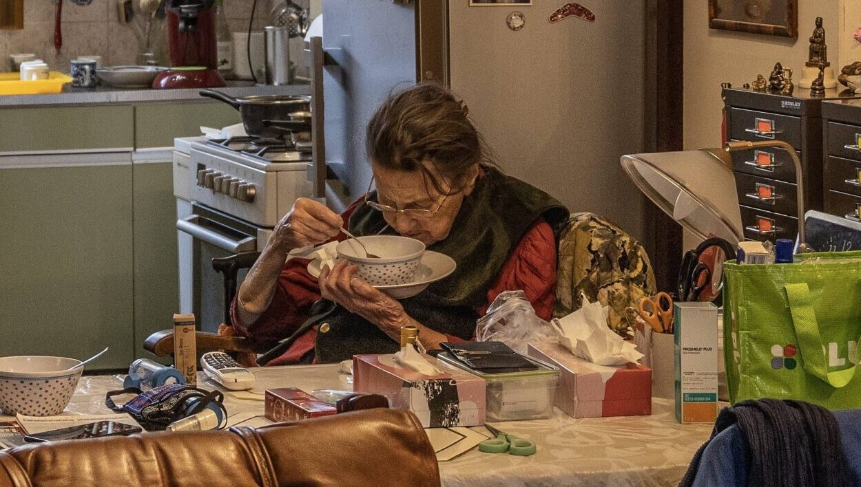 Oudere vrouw eet soep in een druk interieuer