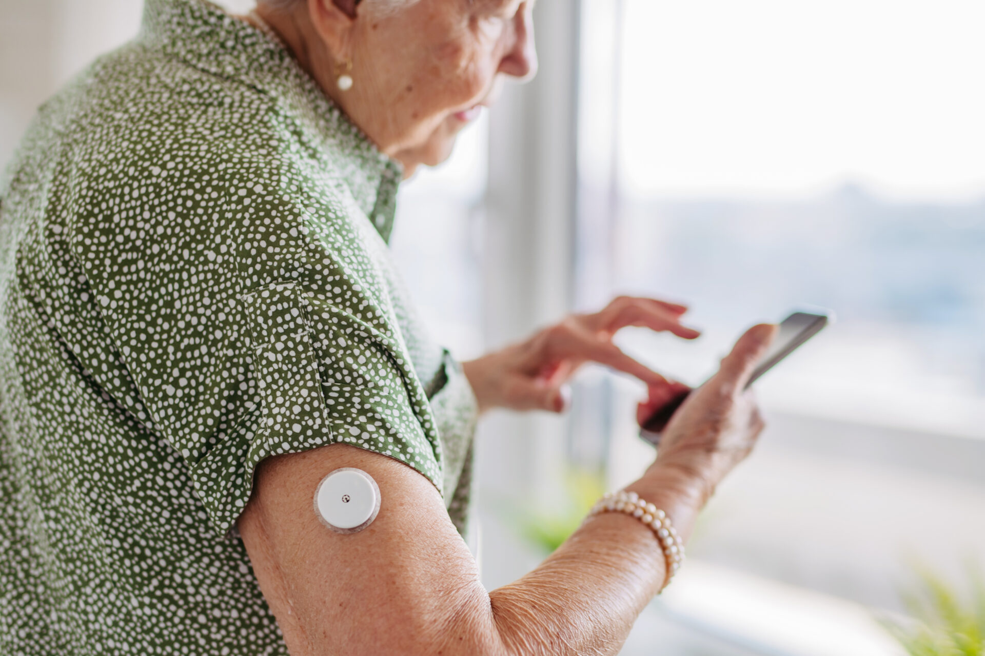 een vrouw met een glucosesensor zit op haar telefoon.