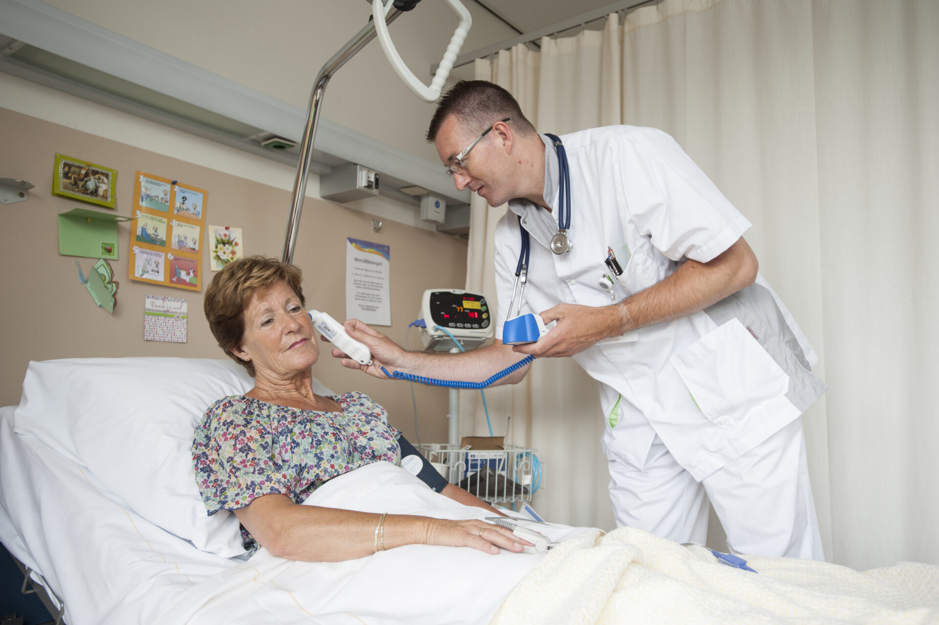 Verpleegkundige neemt de temperatuur op met een digitale oor thermometer.