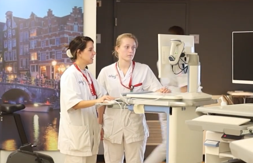 2 verpleegkundigen in overleg bij een computer on wheels