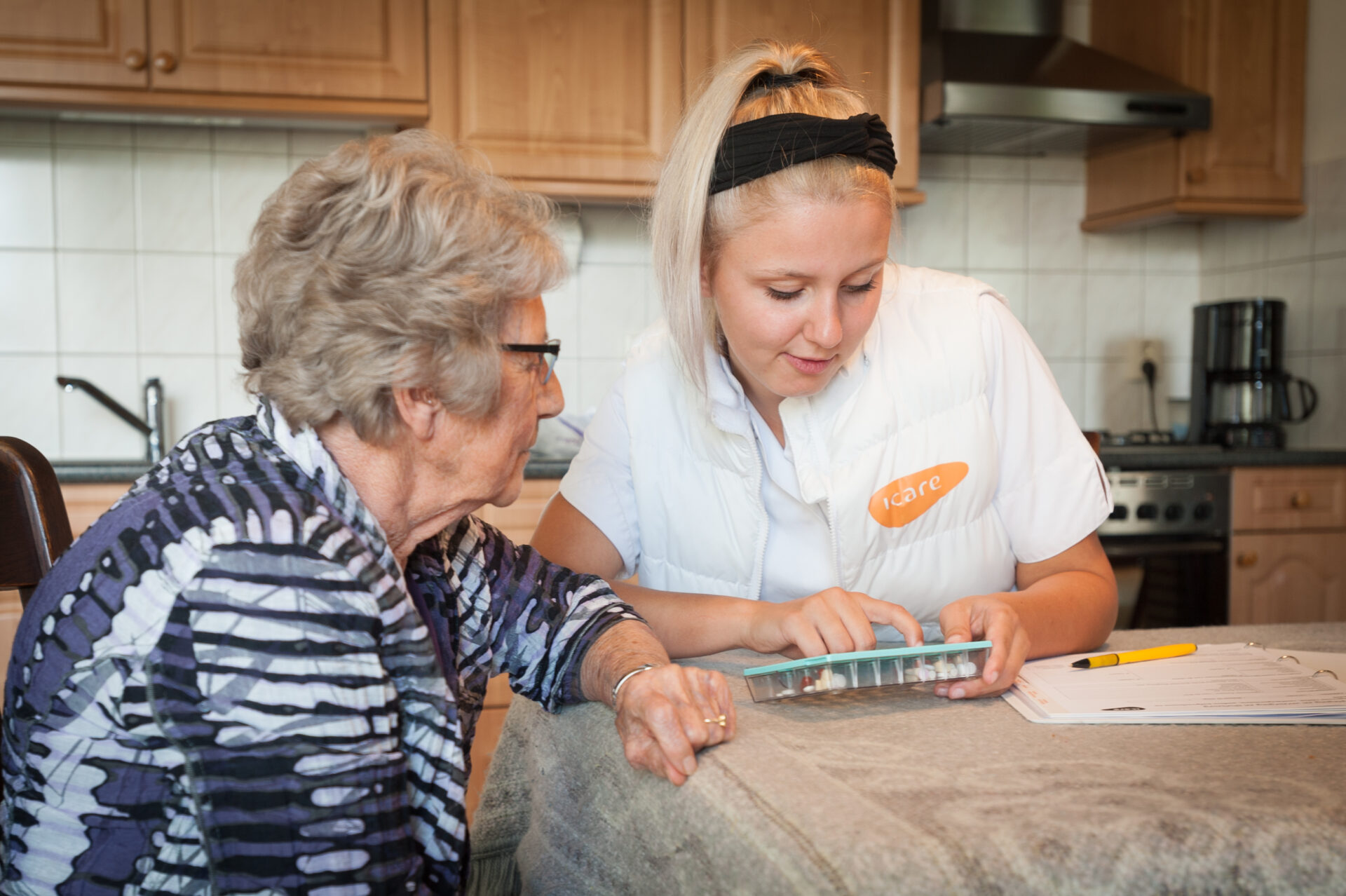 Wijkverpleegkundige legt medicatie uit aan cliënte.