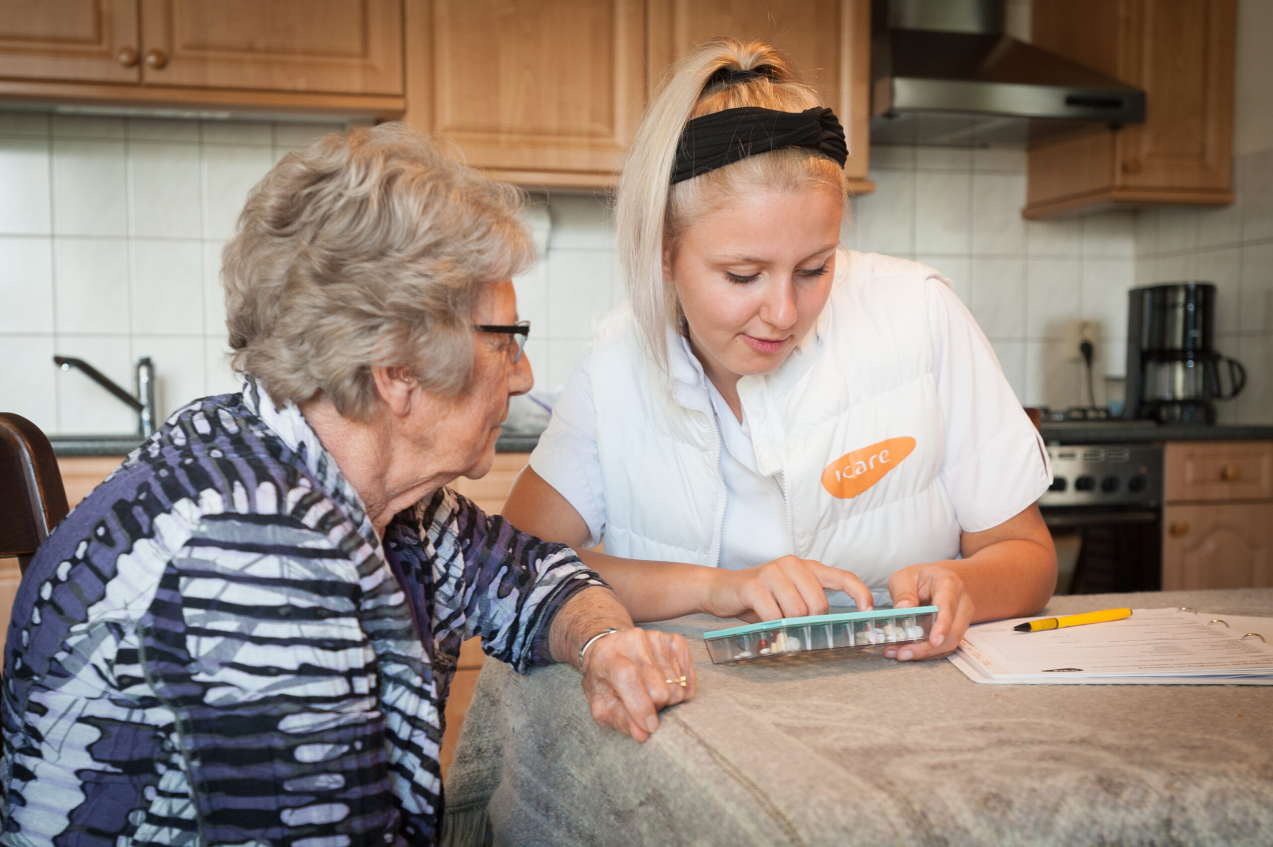 Wijkverpleegkundige legt medicatie uit aan cliënte.
