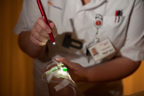 Een verpleegkundige schijnt in de nachtdienst met een klein lampje.
