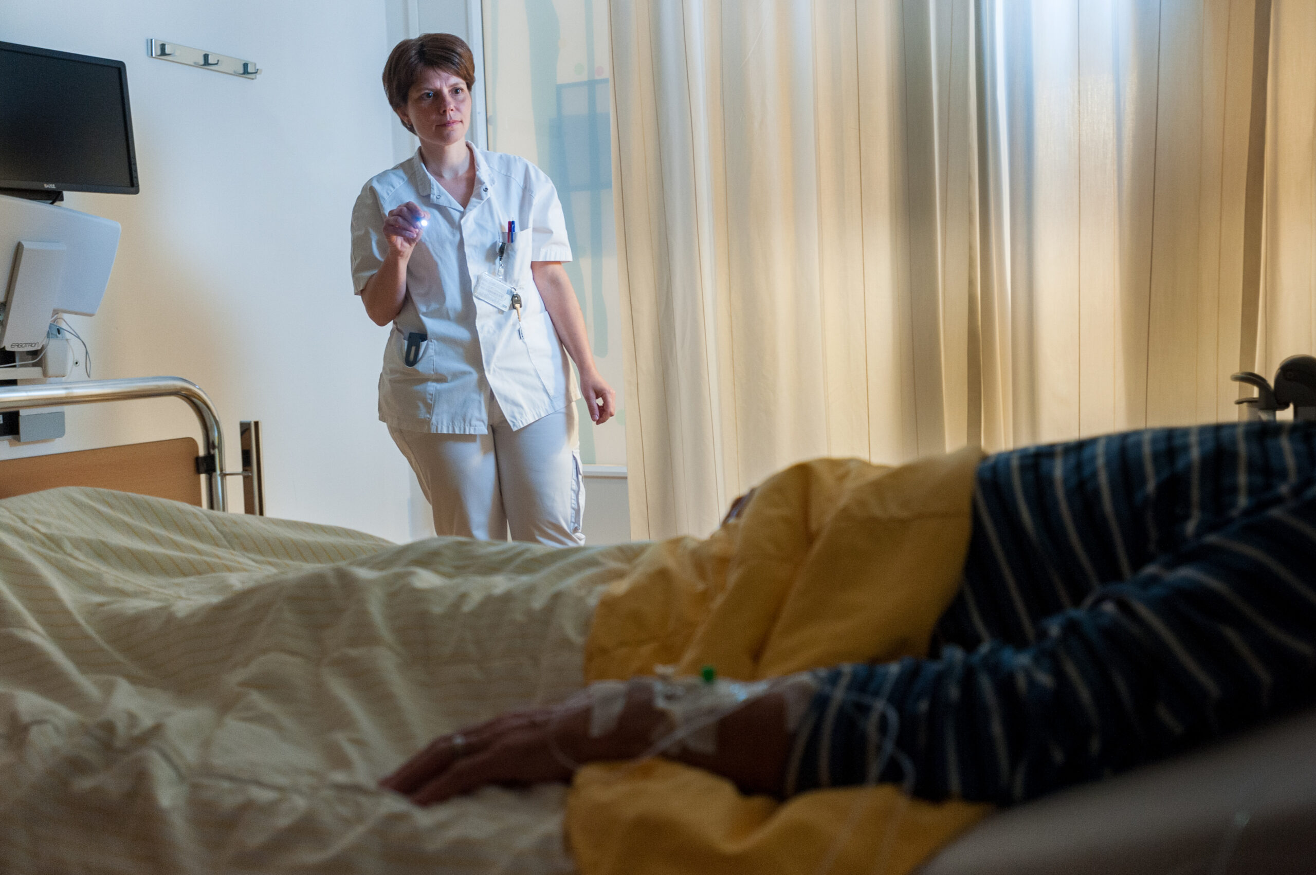 Verpleegkundige kijkt bij patiënt tijdens nachtdienst