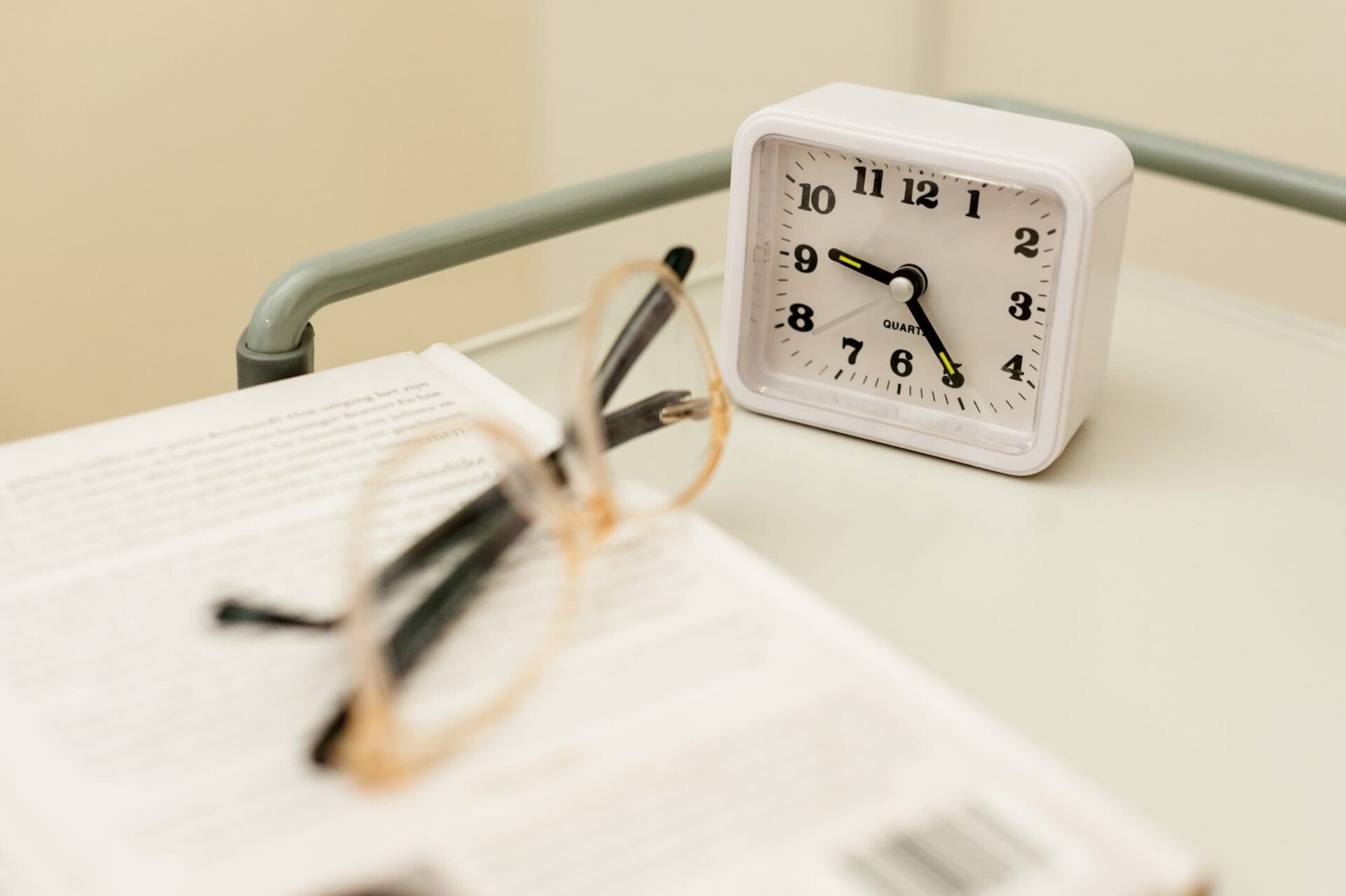 Een bril en een wekker op het nachtkasje van een patient.