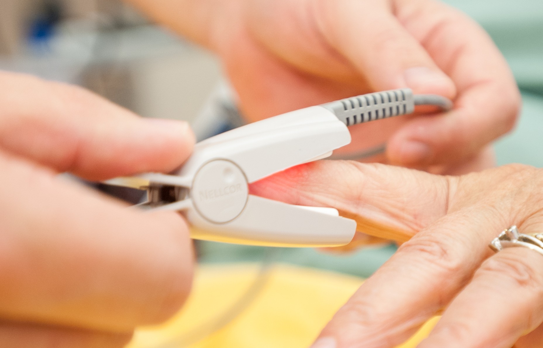 Verpleegkundige plaatst de saturatiemeter op de vinger van de patient.