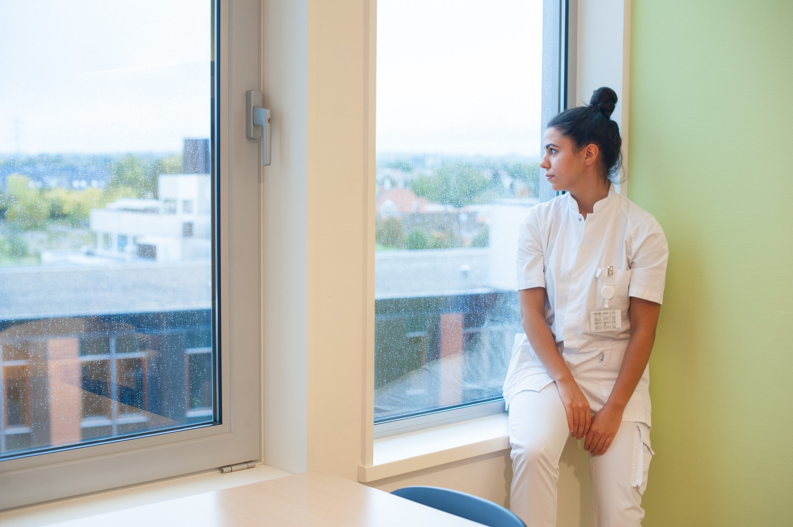 Verpleegkundige kijkt ut het raam van een ziekenhuis, ze kijkt verdrietig. zelfbescherming en agressie